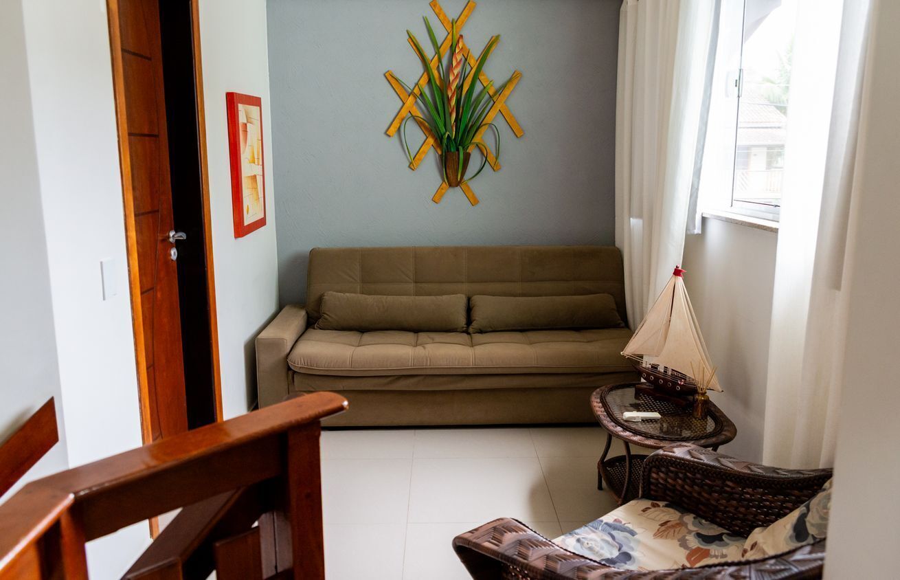 A living room with a sofa, a small table with a ship model, and a wall-mounted plant.