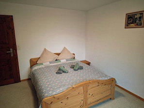Une chambre à coucher avec un lit en bois, une literie à motifs floraux et une porte.
