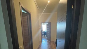 A hallway with wooden flooring, a doormat, and a door leading to another room. - Wonderful 2-bedroom apartment with AC in vibrant Yerevan 🫶✨💖 (Yerevan)