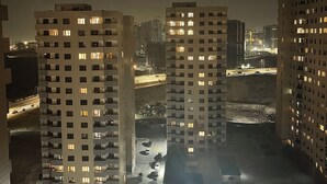 A nighttime view of high-rise residential buildings with illuminated windows, a central road with vehicles, and a playground area. - Wonderful 2-bedroom apartment with AC in vibrant Yerevan 🫶✨💖 (Yerevan)