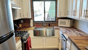 A kitchen with white cabinets, a stainless steel refrigerator, a microwave, and a sink.