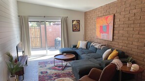 A living room with a sofa, armchair, coffee table, and a rug.