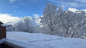 Paisaje nevado con un muro de piedra y árboles.