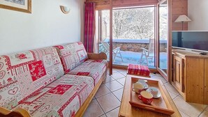 Una sala de estar con un sofá, un aparador de madera, un televisor y una mesa con tazas.