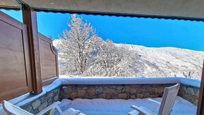 Un espacio exterior con dos sillas blancas y un muro de piedra de fondo.