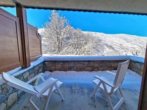 An outdoor seating area with two white chairs and a stone wall backdrop. - 100m from ski slopes, Ground floor, swimming pool, terrace, tv, ski locker, 32m², Les Menuires (Les Menuires)