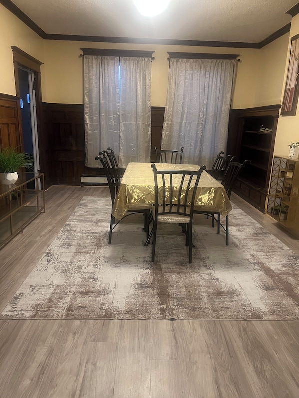 A dining area with a table and chairs, a wooden floor, and a door.