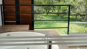 Un bain à remous doté d’une paroi en verre, d’une porte en bois et offrant une vue sur un paysage verdoyant.