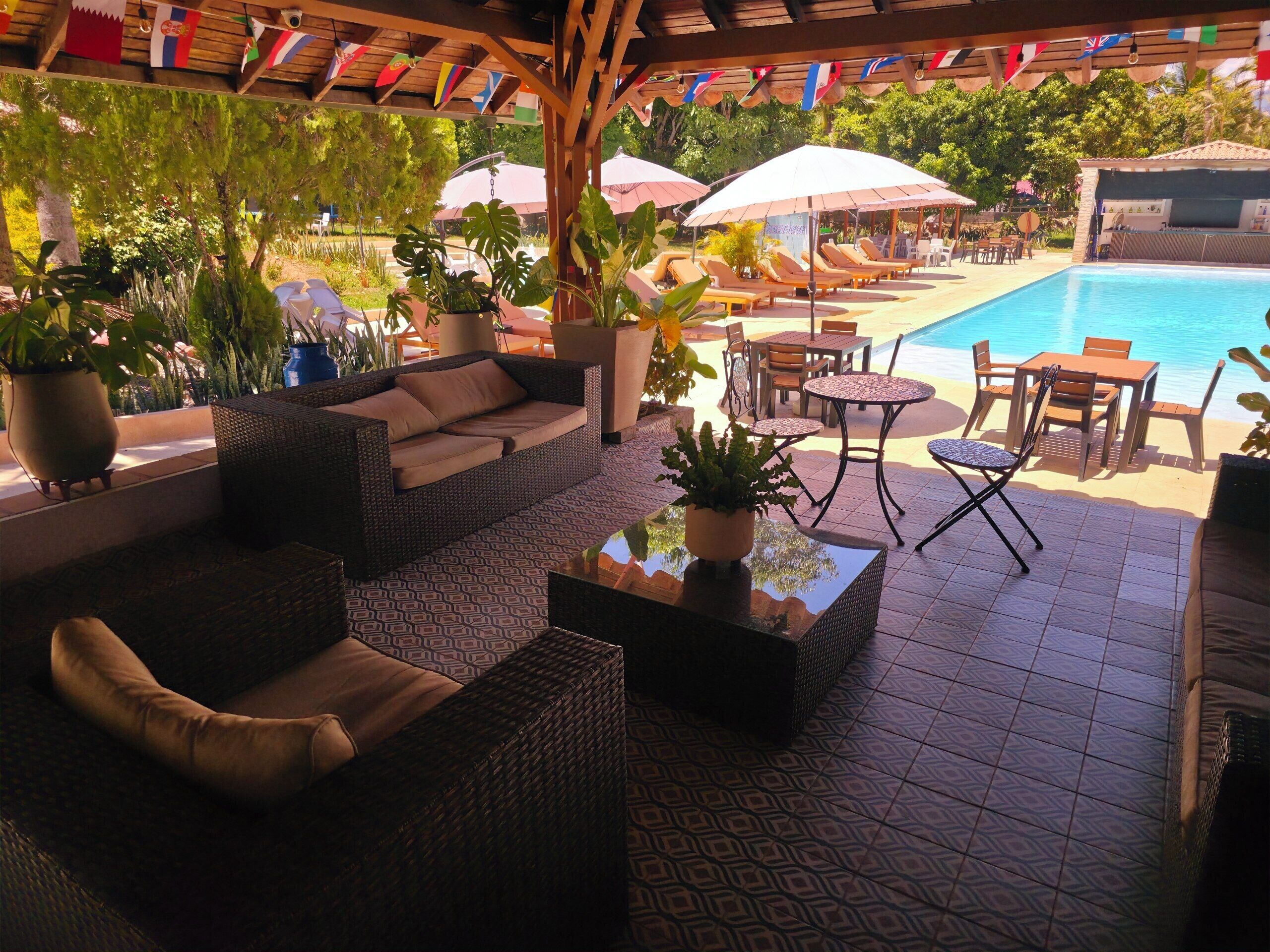A poolside area with wicker furniture, umbrellas, and potted plants.