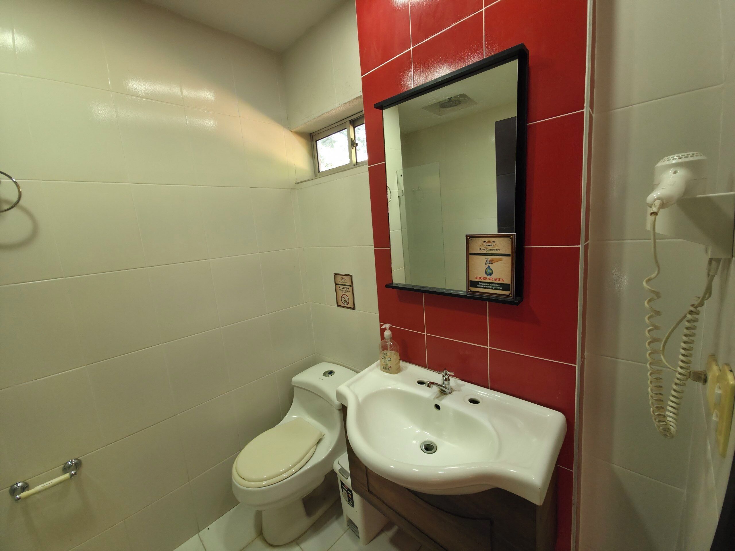 A bathroom with a toilet, sink, and a hand dryer.