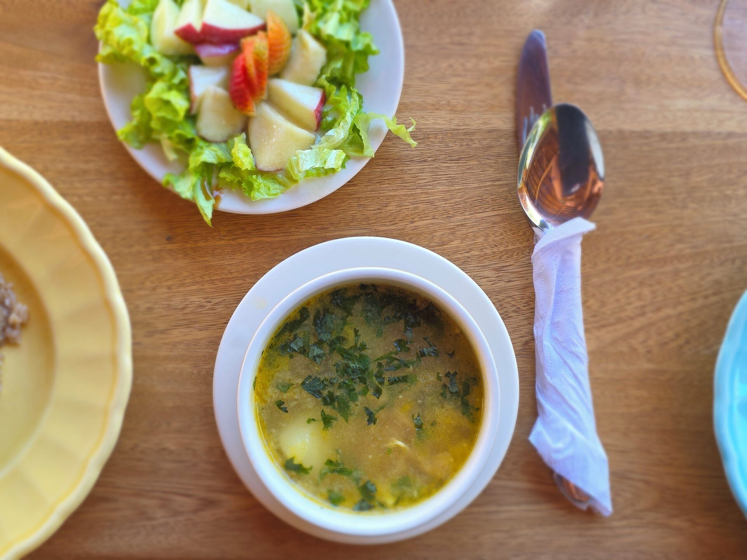 Uma mesa com uma tigela de sopa e uma salada.