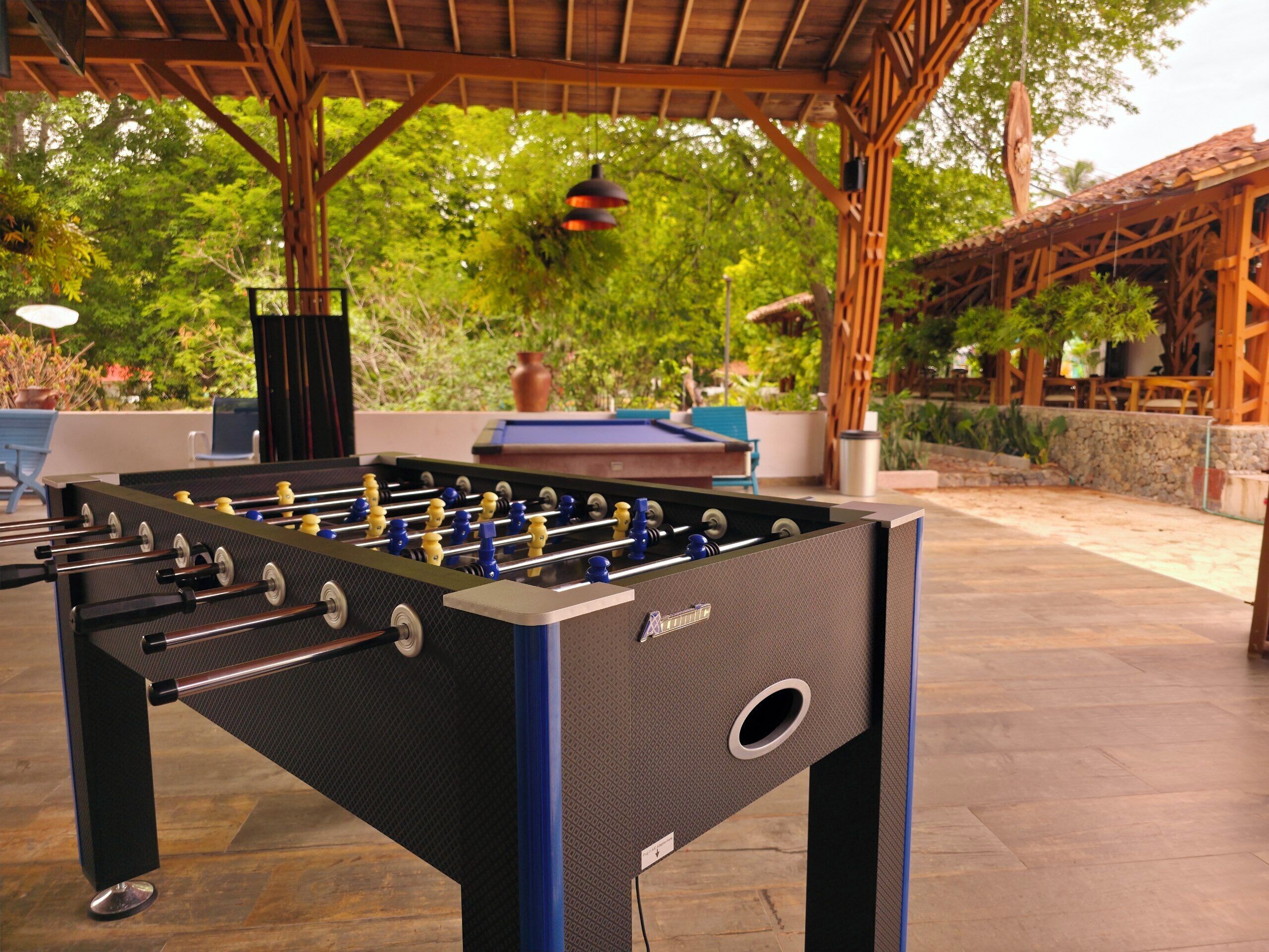 Una mesa de fútbol de mesa en un espacio exterior, cubierta por una pérgola de madera.