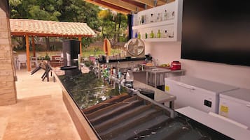 An outdoor bar area with a counter, seating, and a fan.