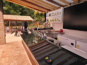 An outdoor bar area with a counter, seating, and a fan.