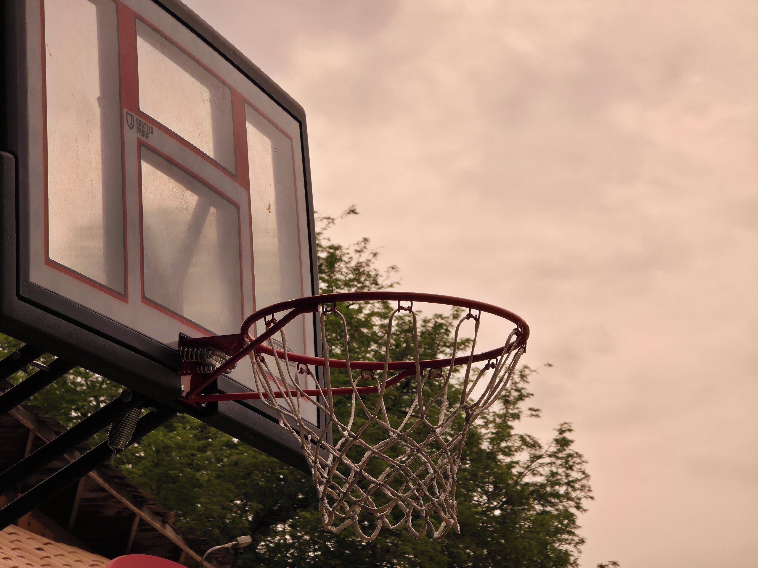 Un canestro da basket fissato a una parete, con una finestra nelle vicinanze.