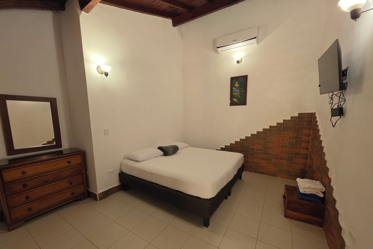 A bedroom with a bed, dresser, and a TV mounted on the wall.