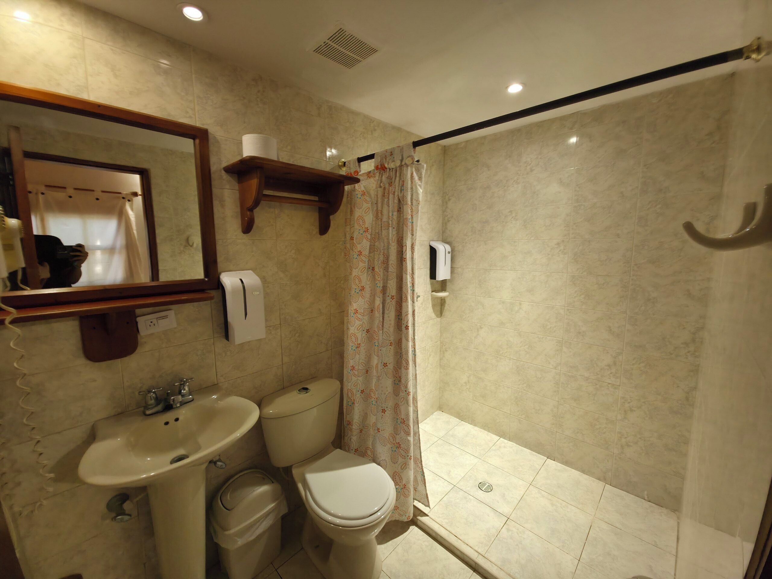 Un baño con lavamanos, inodoro y zona de ducha.