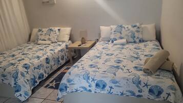 Habitación de hotel con dos camas, cada una con cubrecama y almohadas a juego con motivos náuticos azules.