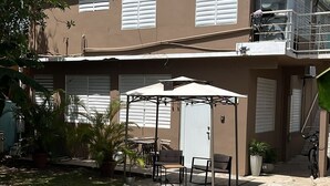 A two-story building with a covered patio area, outdoor seating, and a pathway leading to the entrance. - TROPICAL ESCAPE IN VIEQUES NEAR THE BEACHES (WE HAVE WATER) (Vieques)