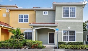 A row of two-story houses with a covered entryway, a small porch, and a front yard with plants. - NEW! Paradise Palms | Private Pool | Resort |Upgraded Wifi | Near Attractions (Kissimmee)