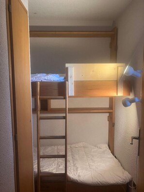 Ein Schlafraum mit Etagenbett, einer Kopfstütze und einer Wandleuchte.