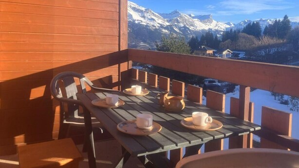 A wooden deck with a table set for tea, overlooking snow-capped mountains. - 200m from ski lifts, 1st floor, balcony, parking, tv, ski locker, 25m², Combloux (Combloux)