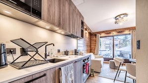 Cozinha moderna com fogão embutido, pia e janela com vista para uma varanda.