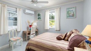 Ein Schlafzimmer mit einem Bett, einem Schreibtisch, einem Stuhl und einem Deckenventilator.