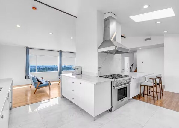 A modern kitchen with a central island, a stove, and a large window. - 3BD 2BA House Breathtaking Views in Los Feliz Hills (Los Angeles)