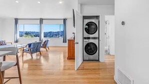 A modern apartment with a dining area, two large windows, and a built-in washer and dryer. - 3BD 2BA House Breathtaking Views in Los Feliz Hills (Los Angeles)