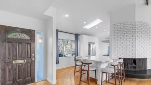 A modern kitchen with white cabinets, a black countertop, and a white brick fireplace. - 3BD 2BA House Breathtaking Views in Los Feliz Hills (Los Angeles)