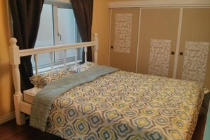 Ein Schlafzimmer mit Bett, Vorhängen, einem Fenster und einem Kleiderschrank.