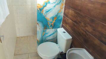 Et badeværelse med toilet, bidet og vægge af marmor.