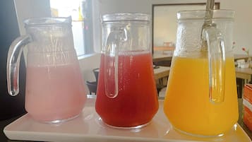 Tres jarras de vidrio con bebidas de diferentes colores sobre una bandeja blanca.
