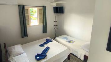 A room with two beds, a ceiling fan, a TV, and a window with curtains.