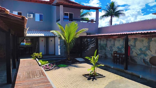 A courtyard with a wooden deck, a palm tree, and a stone wall with a mural.