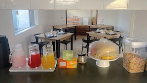 A breakfast buffet setup with various food and drink options, including cereal and juices.