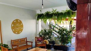 A room with a wooden bench, a small table, a potted plant, and a wall decoration.