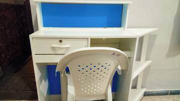 Un escritorio blanco con pantalla azul, una silla blanca con detalles azules y un piso de baldosas.