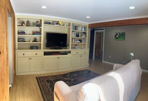 A living room with a sofa, a coffee table, a TV, and a bookshelf.