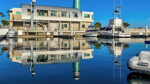 Uma marina com barcos, um farol e um edifício com a placa 'MARINA SERVICE'.