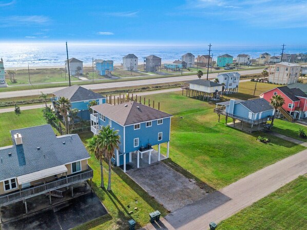 A coastal residential area with houses, a beach, and a clear sky.