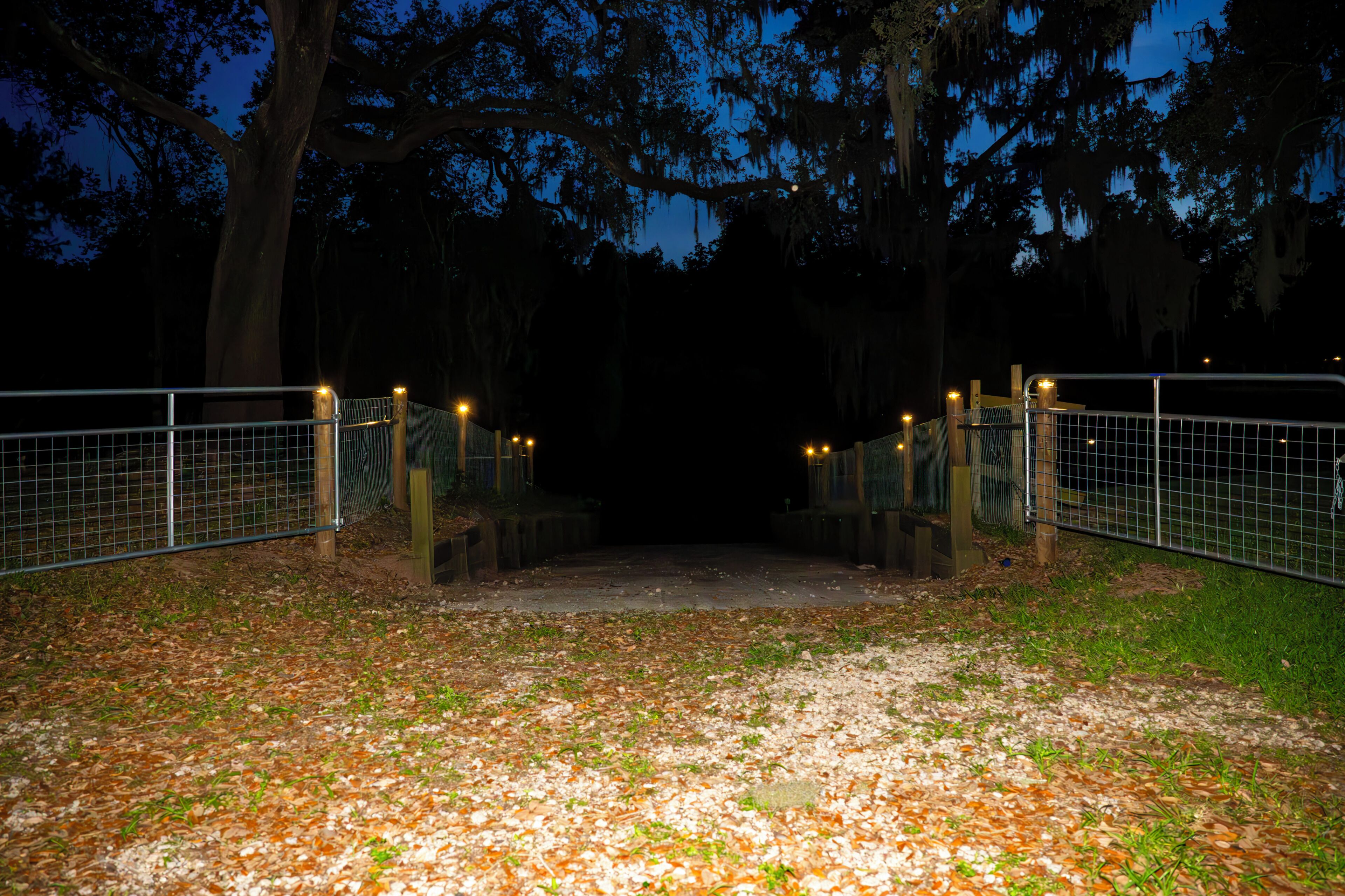 A gated pathway leading to a building surrounded by trees.