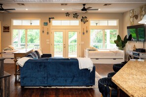 A living room with a blue sofa, a dining area with a granite table, and a TV mounted on the wall. - Mount Olive Ranch (West Columbia)