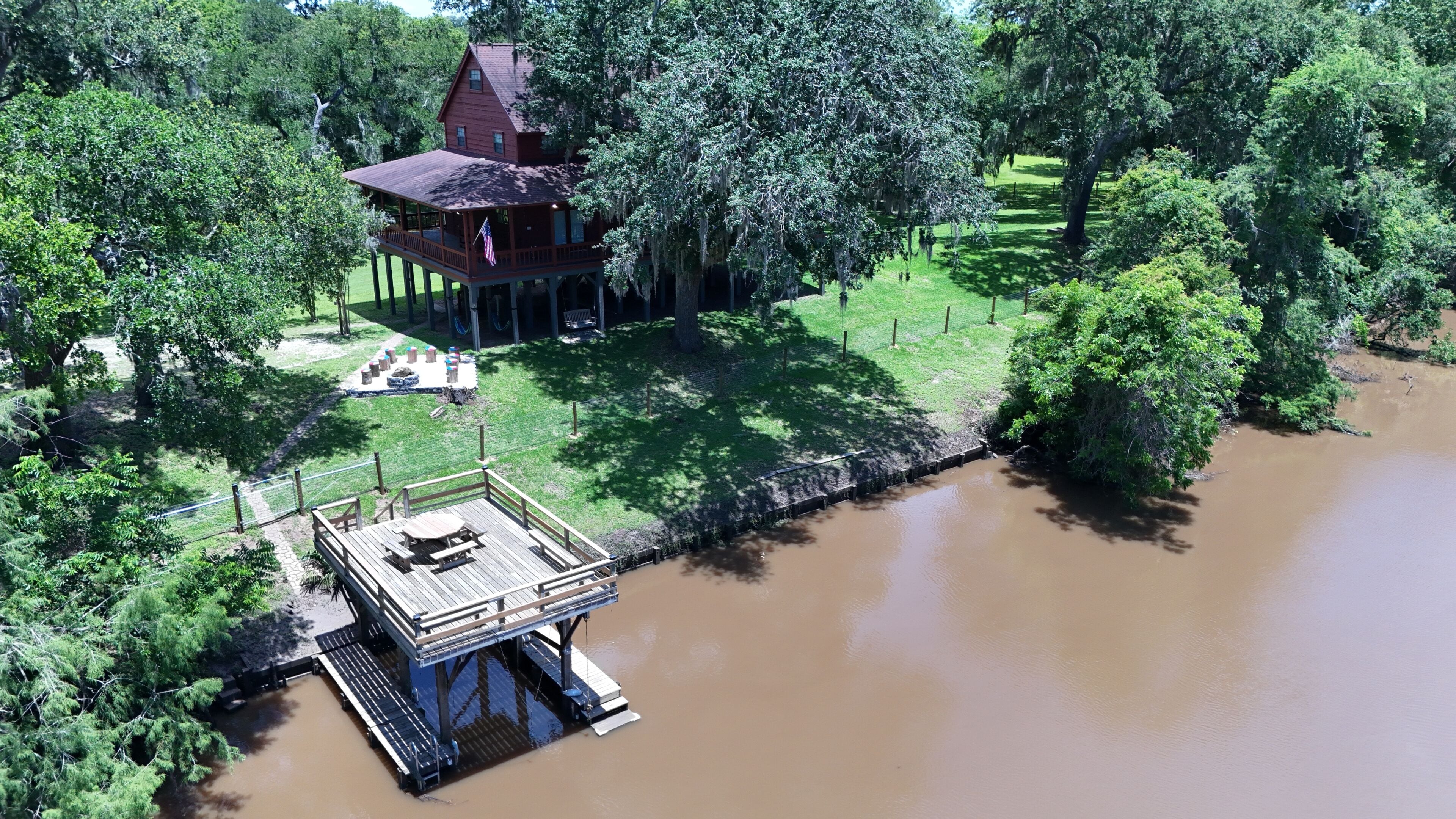 Ein Holzhaus mit Veranda und einem Steg, der in einen Fluss führt.