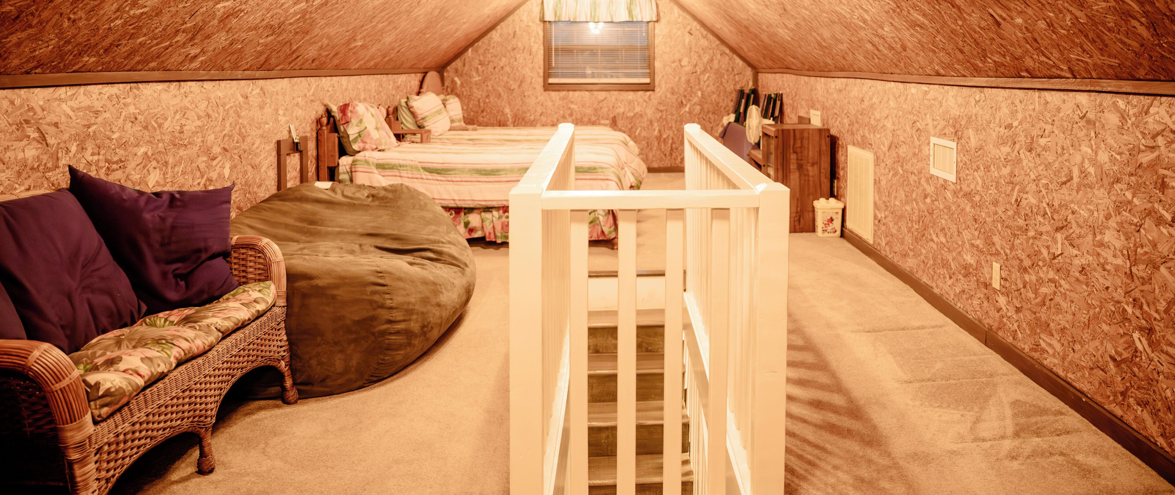 Una camera da letto mansardata accogliente con un letto a castello, un piccolo divano e una culla in legno.