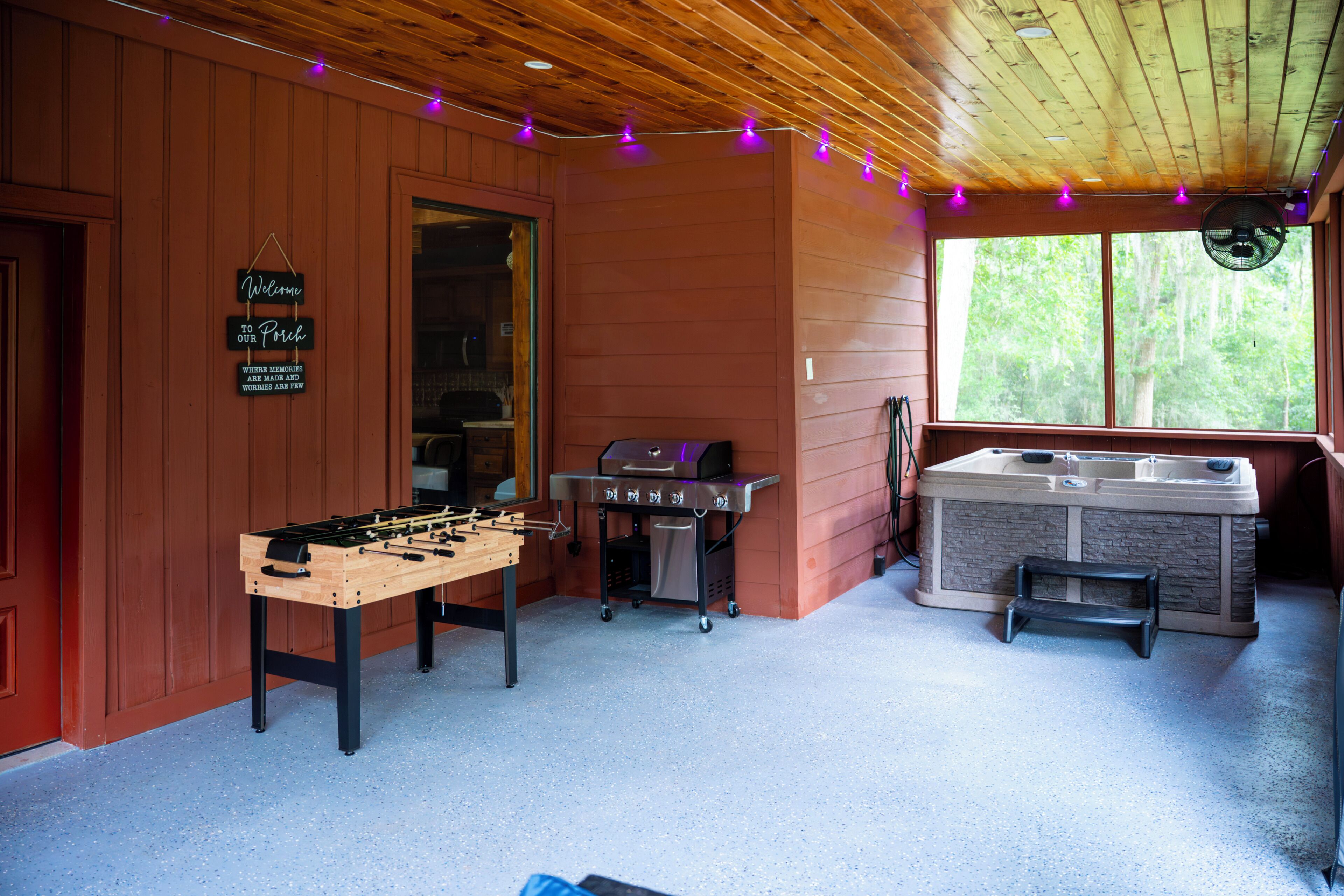 A room with a foosball table, a grill, and a hot tub.