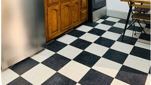 Uma cozinha com armários de madeira, geladeira, fogão e piso xadrez.