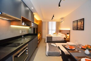 Una habitación de hotel moderna con kitchenette, una cama con vistas y un comedor.