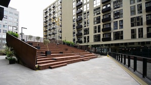 Un bâtiment moderne avec un escalier menant à un étage supérieur, entouré d’autres immeubles de grande hauteur.